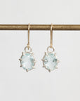 Gold earrings with light blue gemstones on a white background