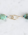 Turquoise beaded necklace with gold clasp on a white background