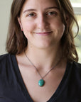 Woman wearing turquoise necklace against a blurred indoor background