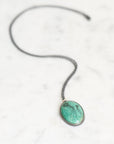 Necklace featuring a bezel set turquoise in oxidized silver. The turquoise features two jellyfish engravings.