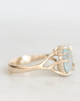 A gold ring with a unique antler-like setting holding a light blue rectangular gemstone, accented with small clear stones, shown on a light gray background.