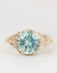 Blue gemstone ring with branchy prongs against a plain background.