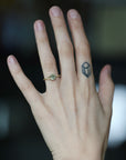 Green stone ring on hand with diamond berries. Hand has tattoo