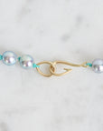 Pearl necklace with a gold clasp on a light gray background