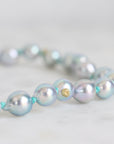Pearl necklace with gold accents on a light gray background