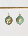 Pair of green earrings with gold accents on a white background