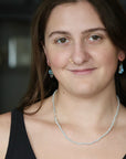 Small white pearl strand necklace on woman with brown hair and nose ring