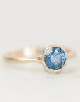 Blue gemstone ring with gold setting and barnacle details.