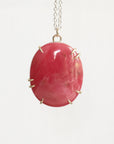 Pink oval stone pendant on a chain against a white background