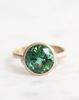 Gold ring with a green gemstone on a white background