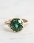 Gold ring with a green gemstone on a white background
