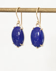 Pair of blue gemstone earrings on gold hooks against a white background