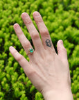 Bright green stone ring with diamonds and branchy prongs on hand