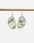 A pair of teardrop-shaped drop earrings with white and green marbled stone inlays set in gold-toned metal, hanging from a gold-toned horizontal bar against a light gray background.