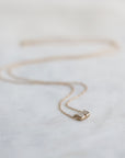 Gold necklace with a small diamond pendant on a light fabric background