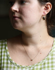 Close-up of a person wearing earrings and a necklace with a green and white checkered top.