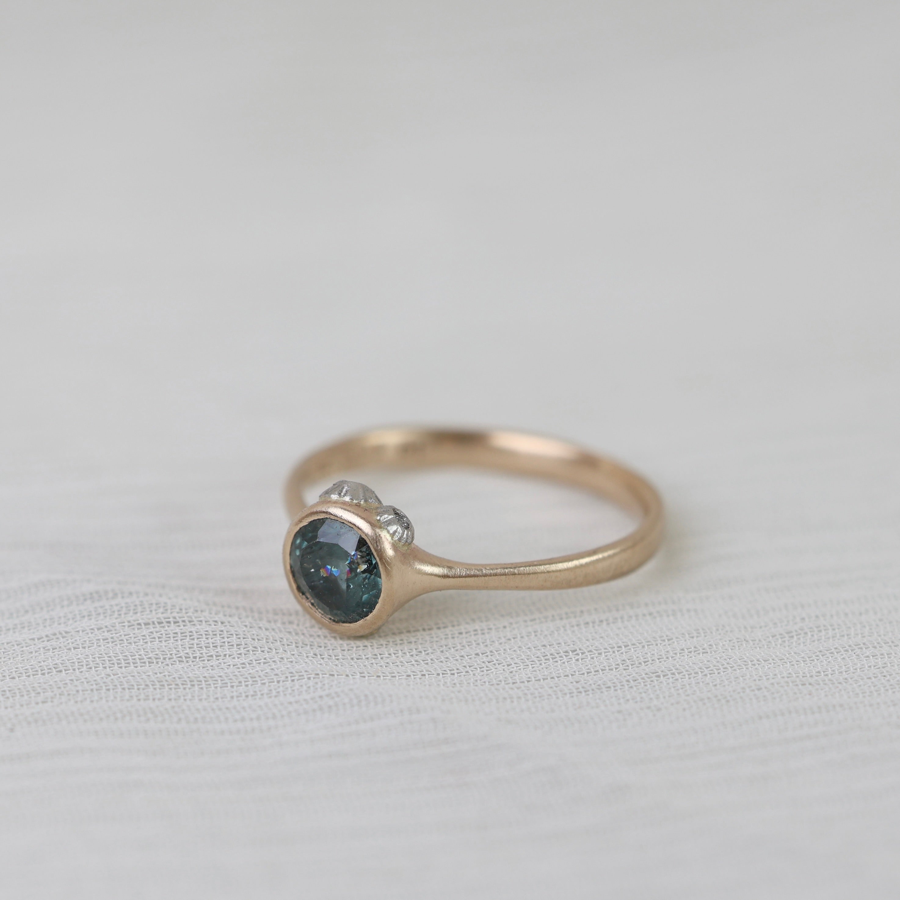 Gold ring with a blue gemstone on a light fabric background