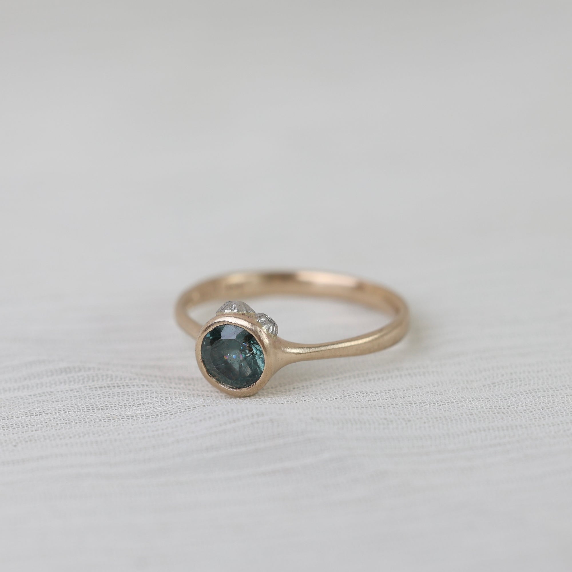 Gold ring with a blue gemstone on a white fabric background