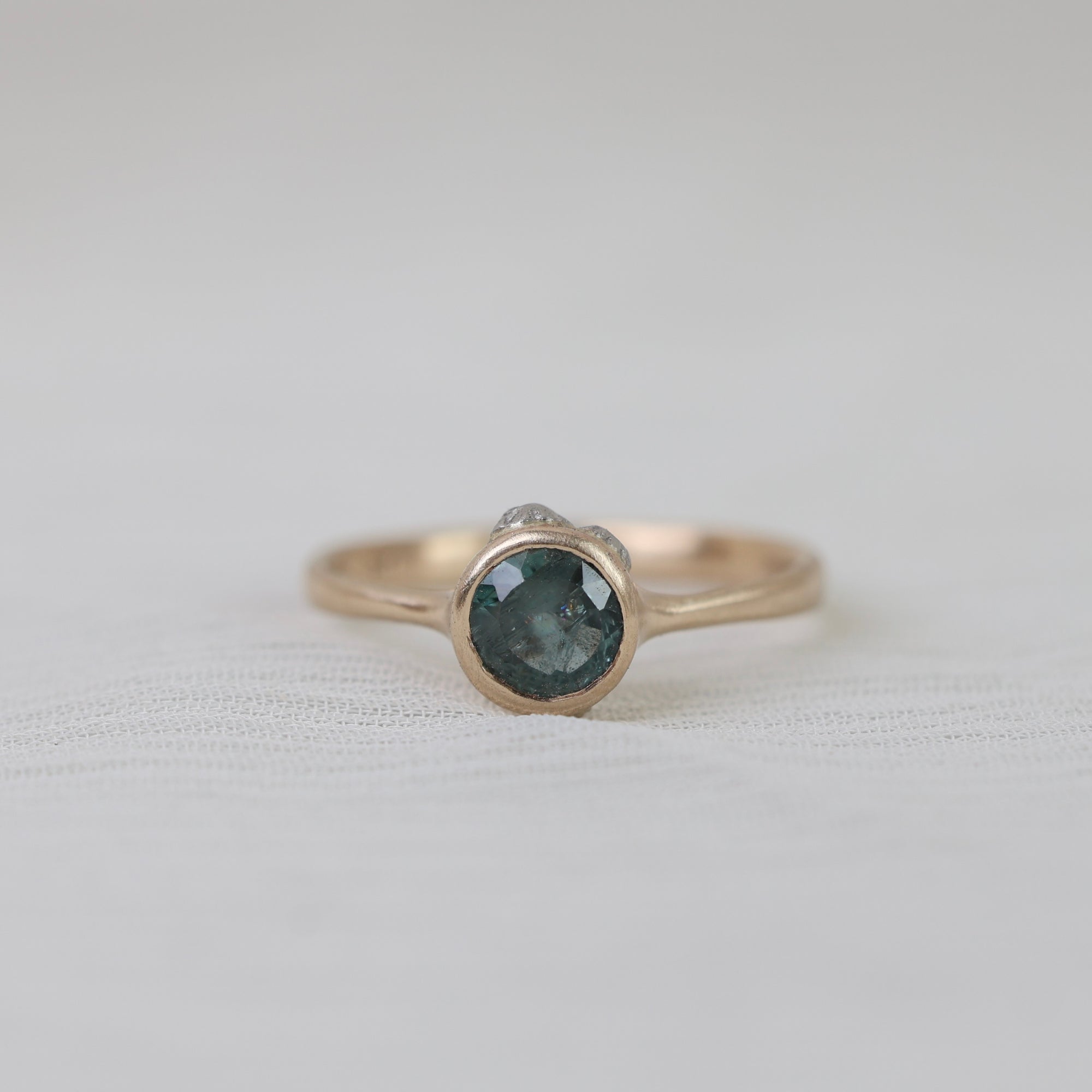 Gold ring with a dark gemstone on a light gray background