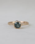 Gold ring with a dark gemstone on a light gray background