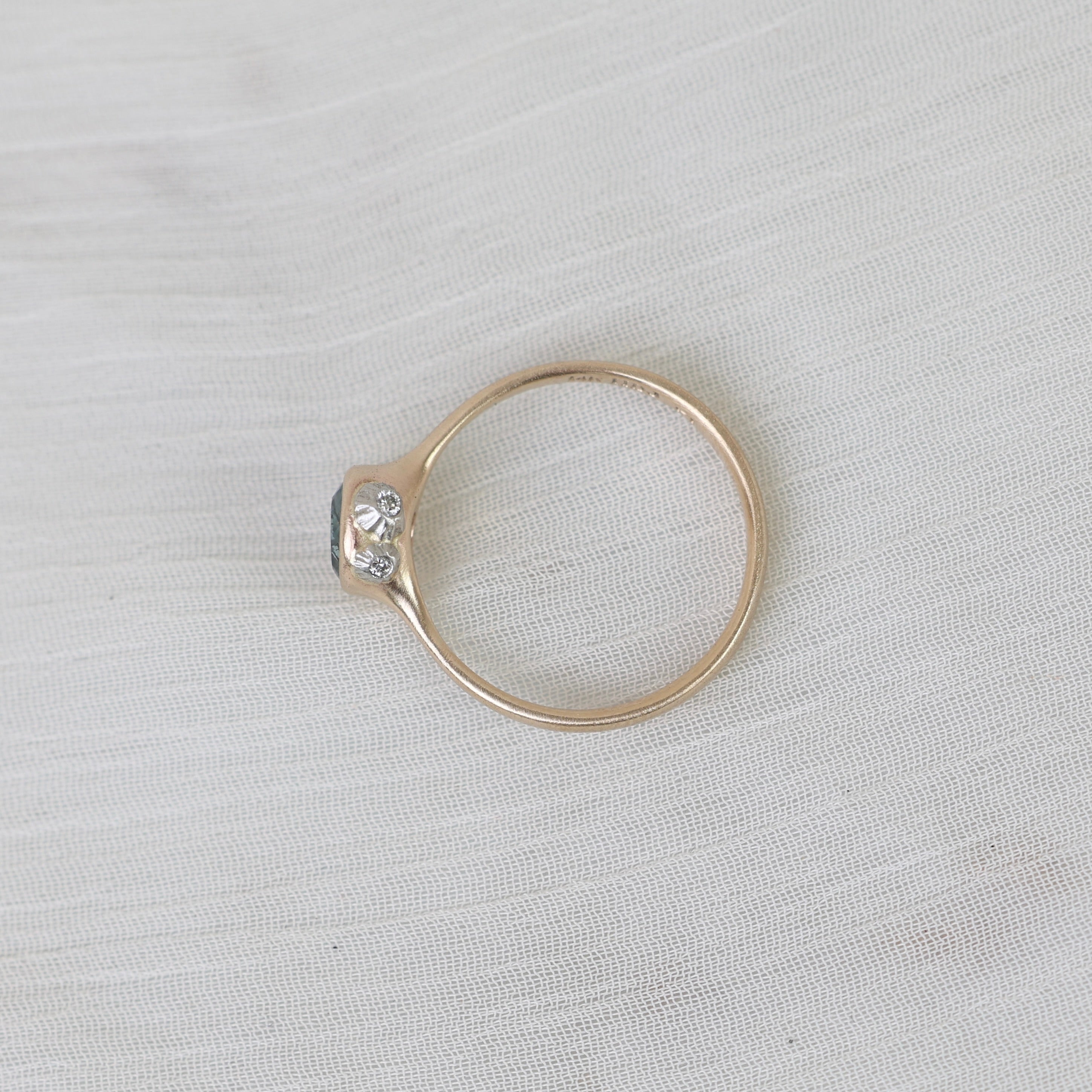 Gold ring with a diamond on a light gray fabric background