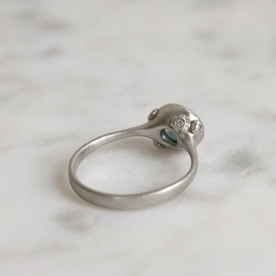 Silver ring with gemstones on a marble surface