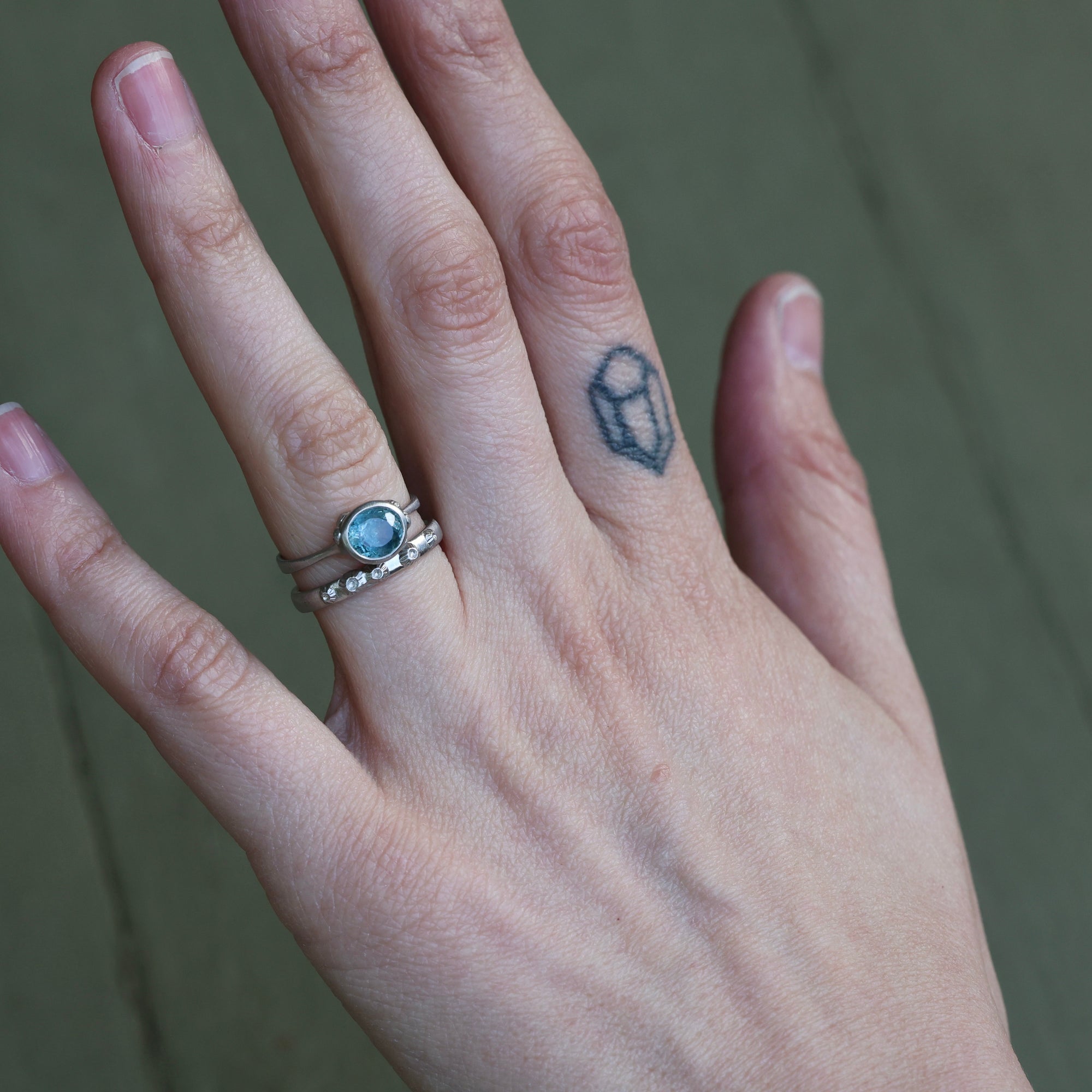 hand wearing blue gemstone ring and solid platinum band with barnacle details 