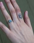 hand wearing blue gemstone ring and solid platinum band with barnacle details 