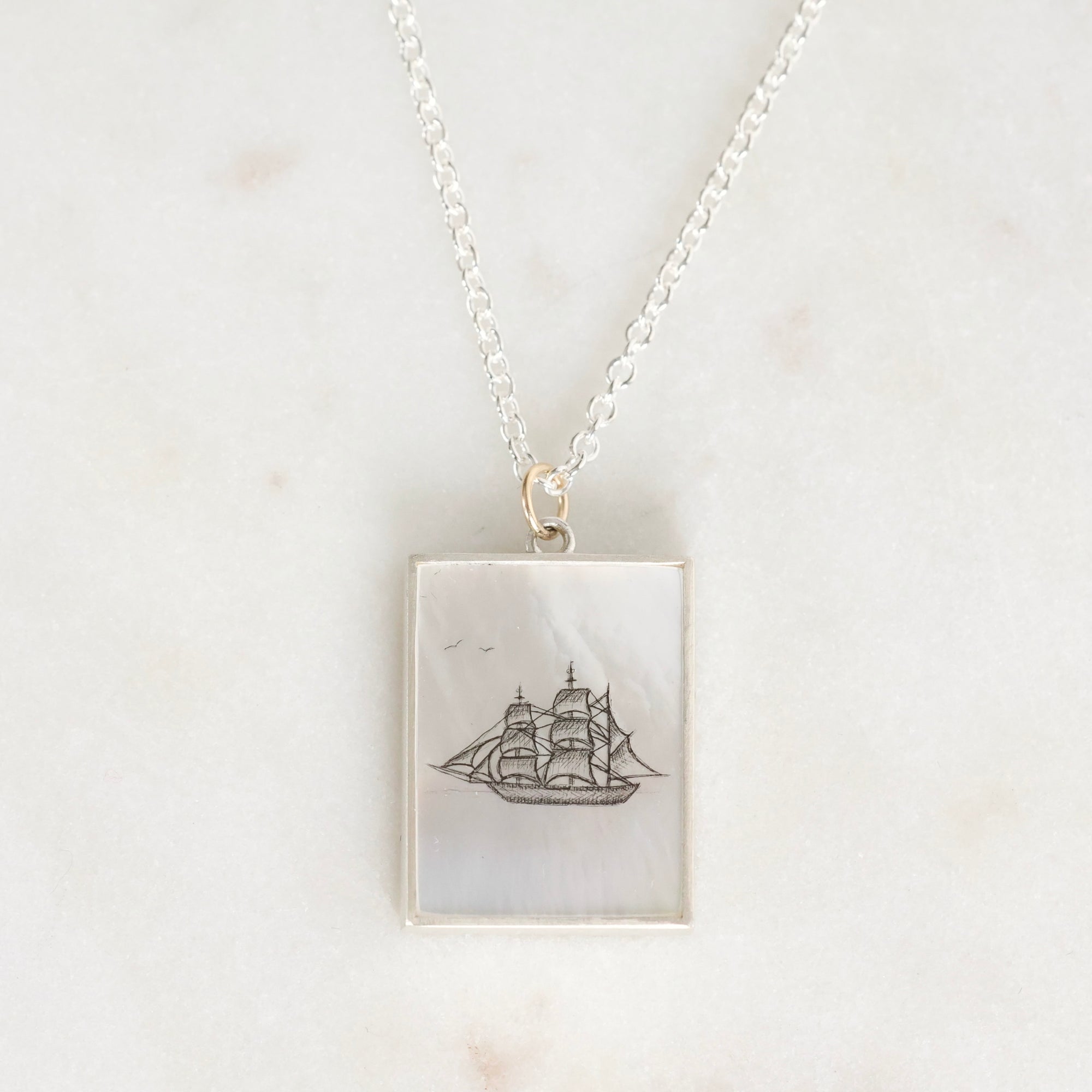 Necklace with a pendant featuring a ship design on a light background