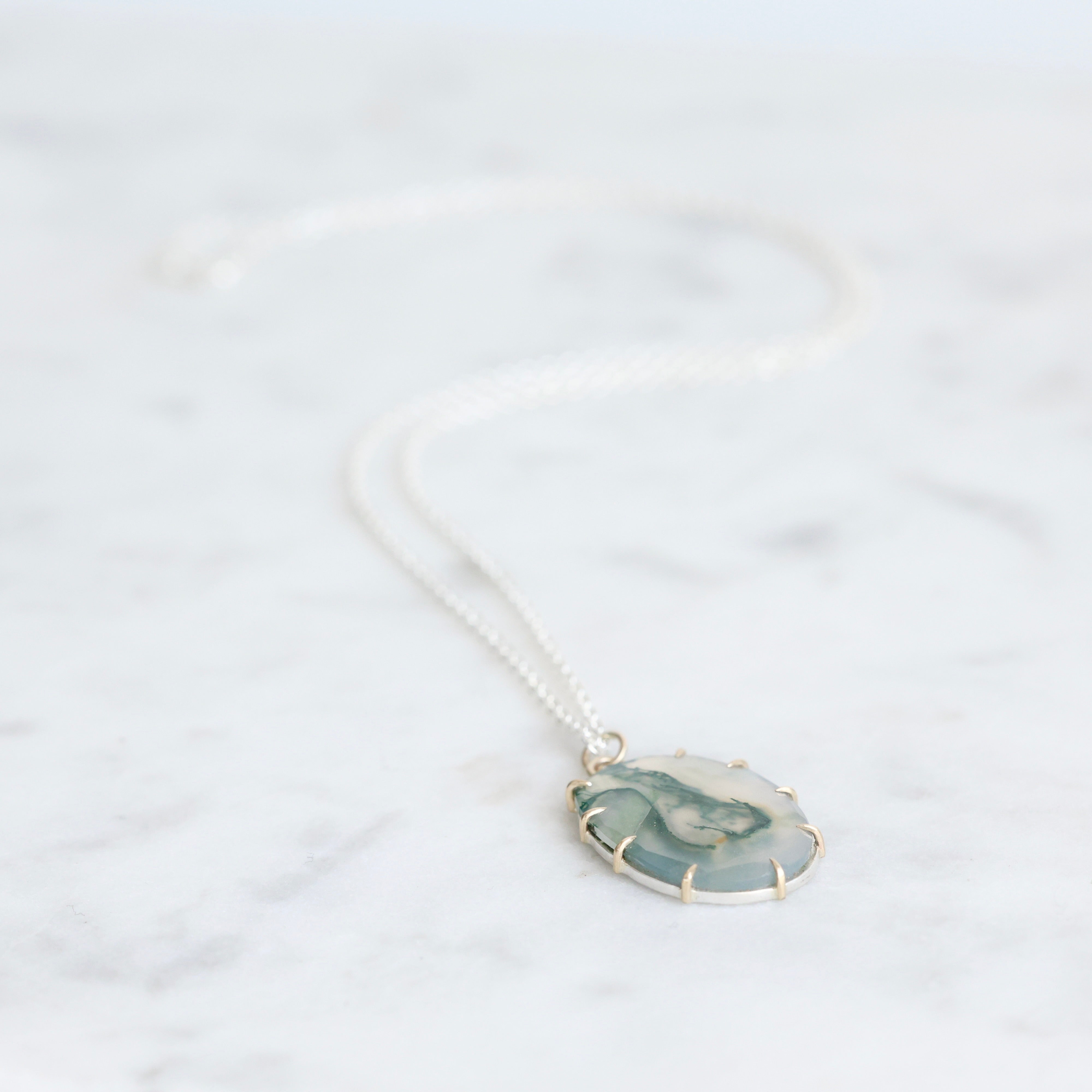 Necklace with a green and gold pendant on a white background