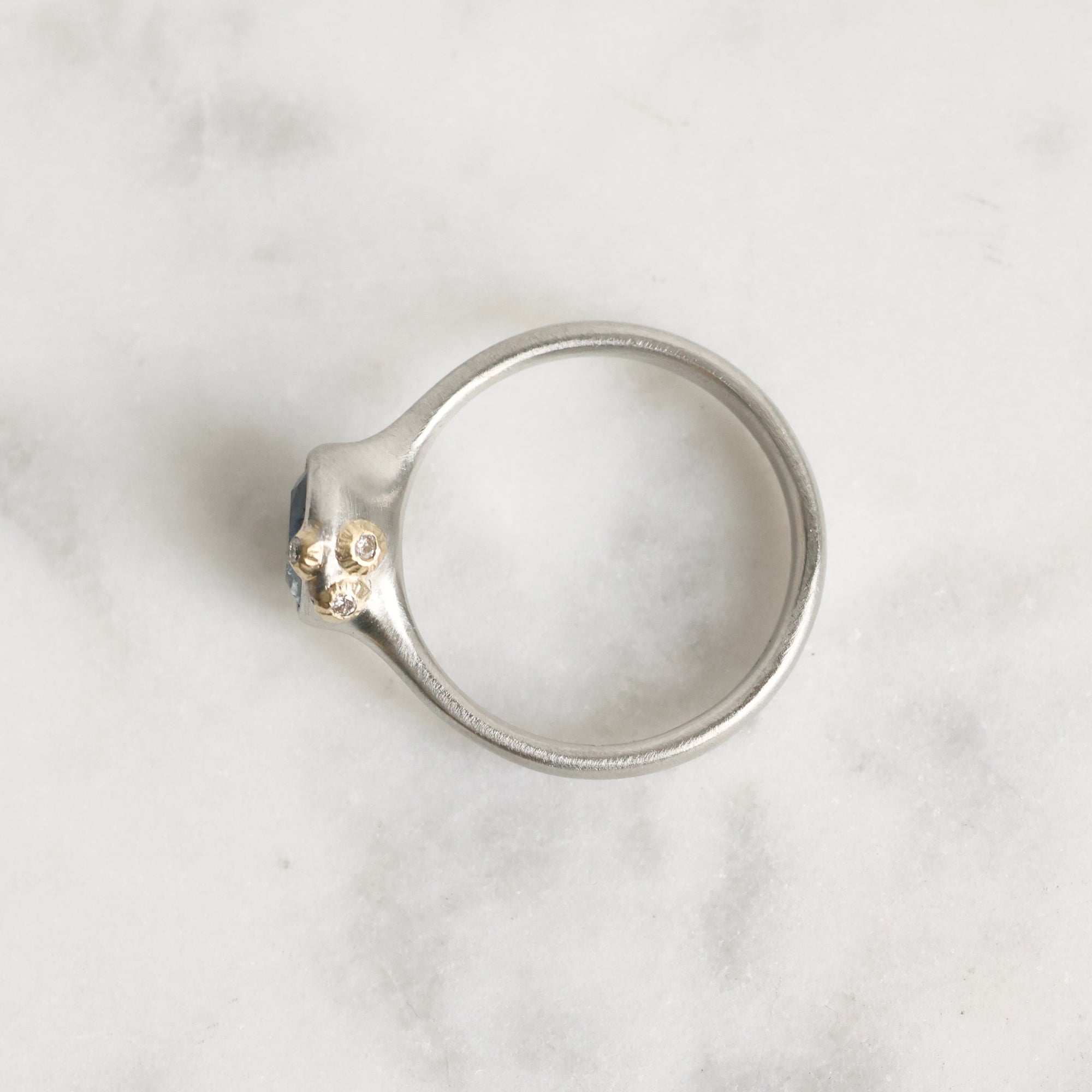 Silver ring with a small gemstone on a marble surface