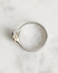 Silver ring with a small gemstone on a marble surface
