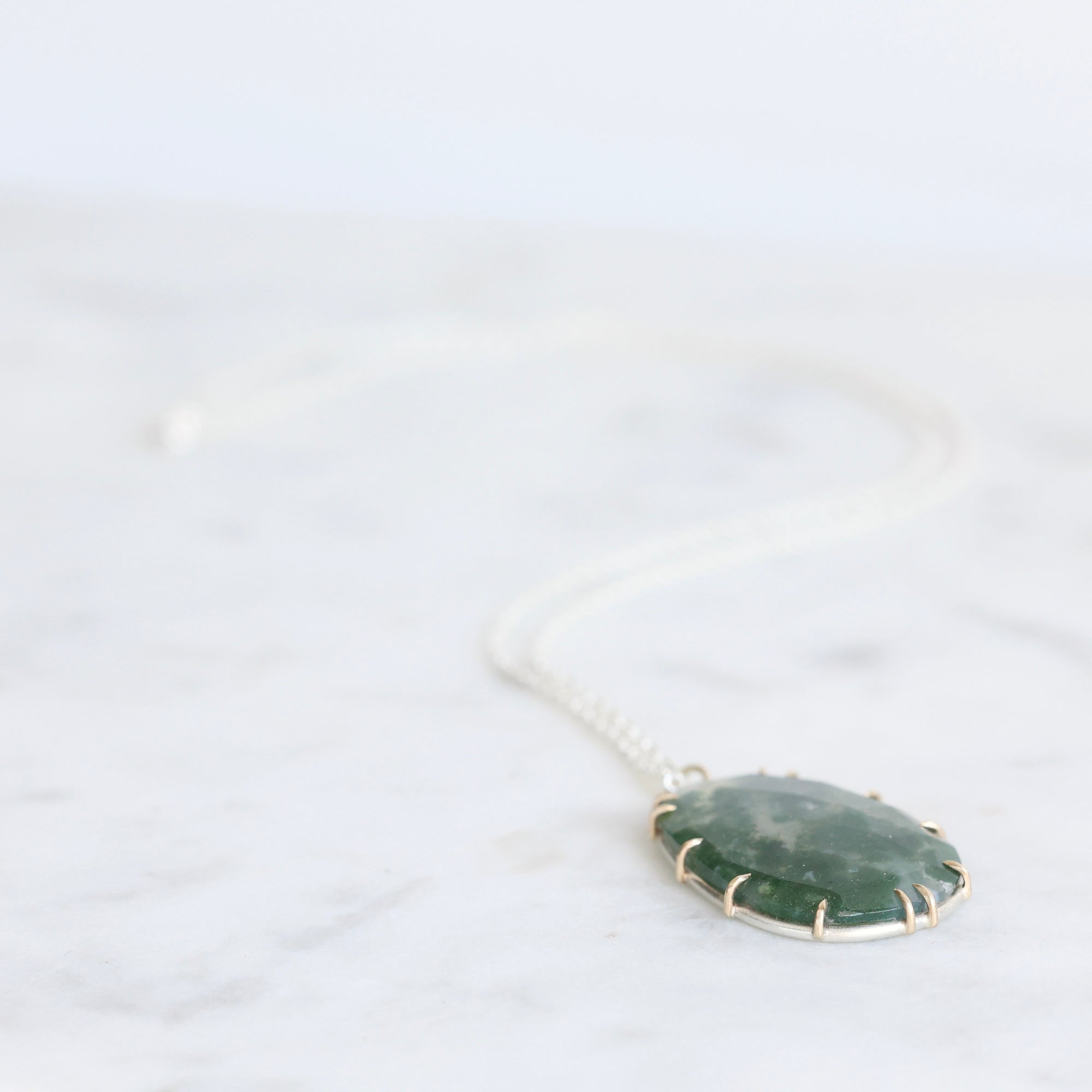 Necklace with a green stone pendant on a white background