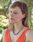Woman wearing an orange top and a necklace with green beads outdoors
