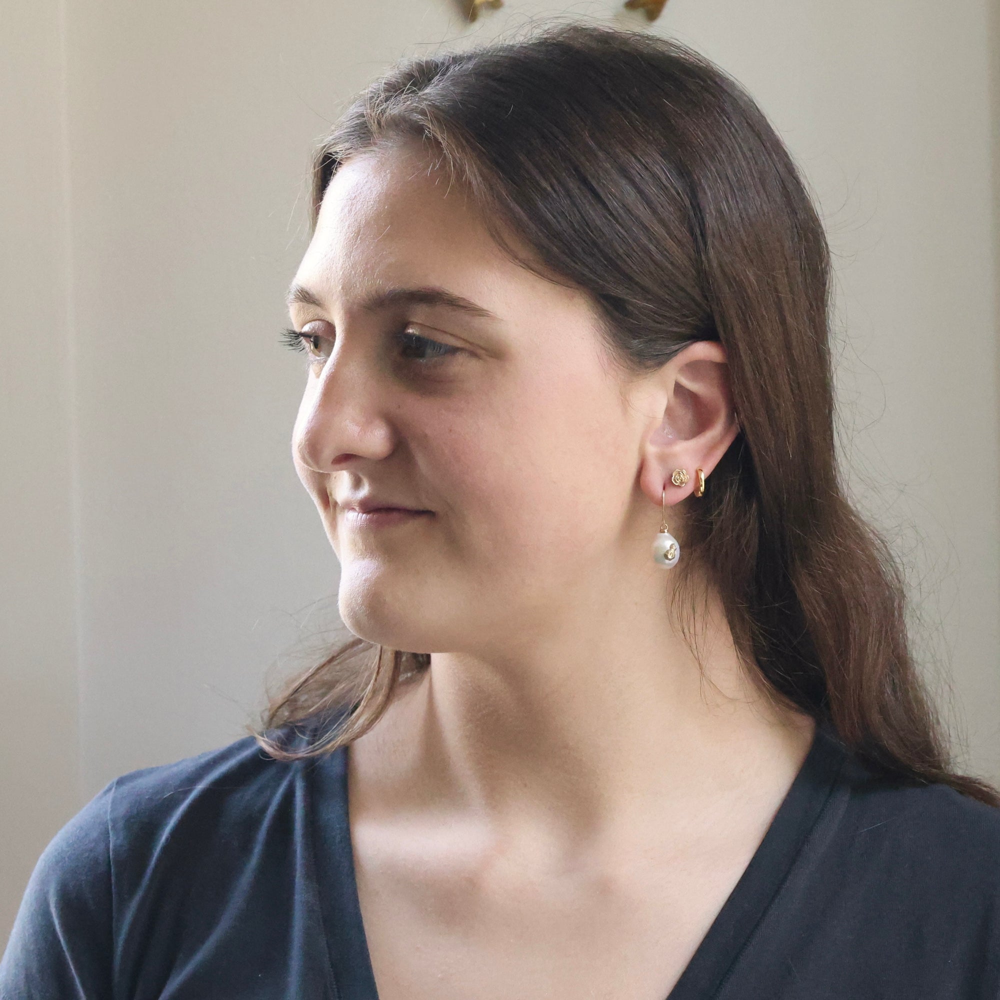 Woman with a side profile, wearing earrings, against a neutral background