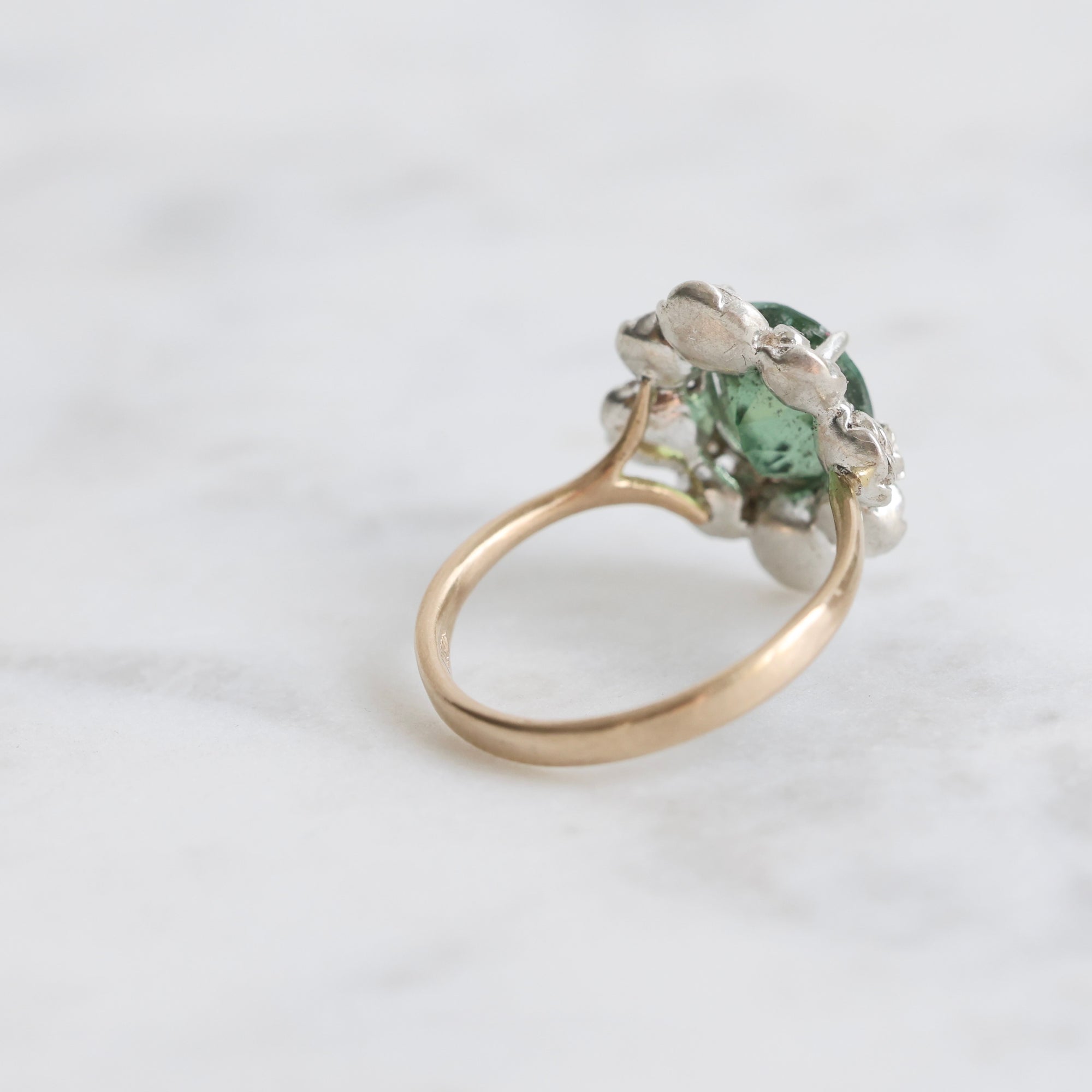 Ring with a green gemstone on a light gray background