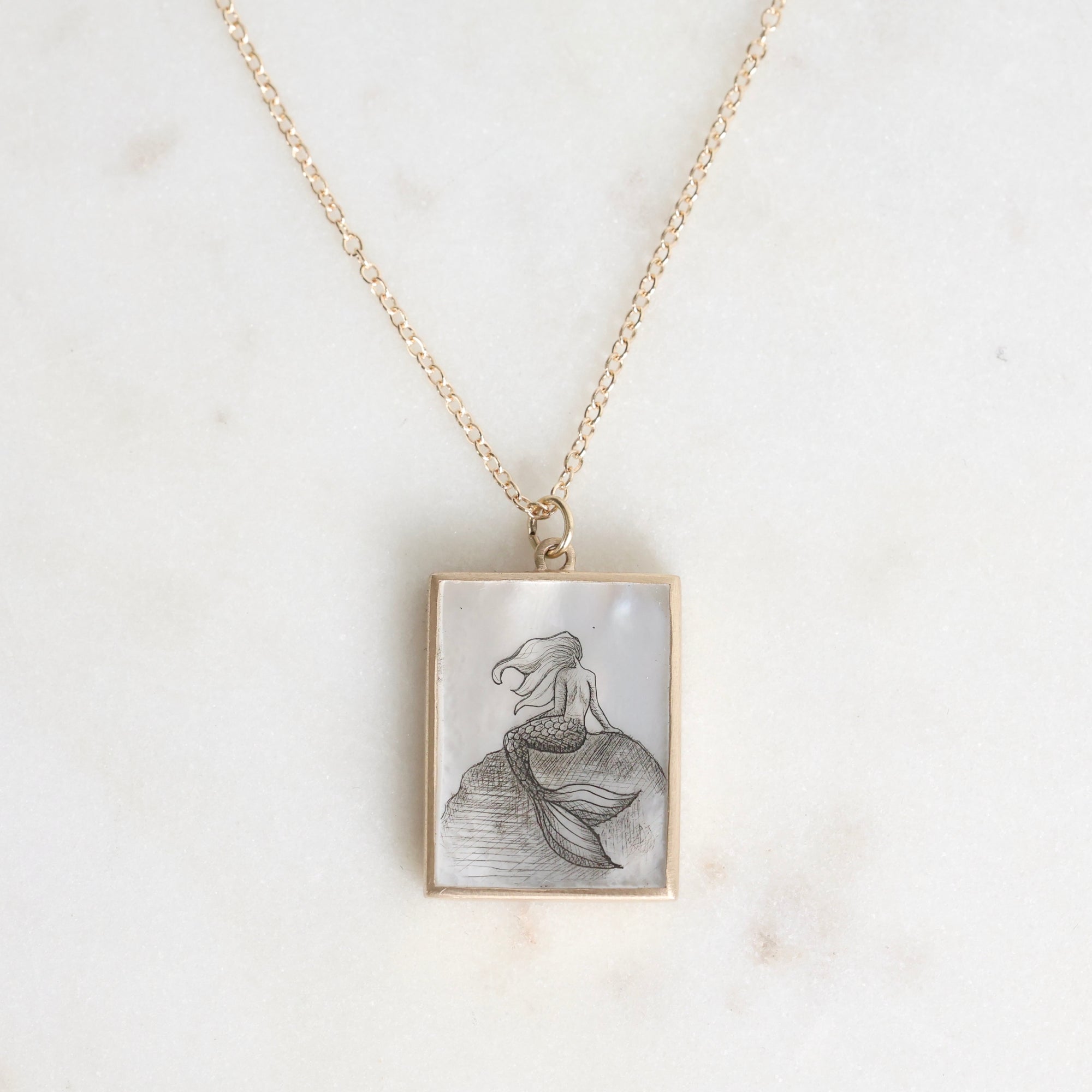 Necklace with a pendant featuring a mermaid design on a light background