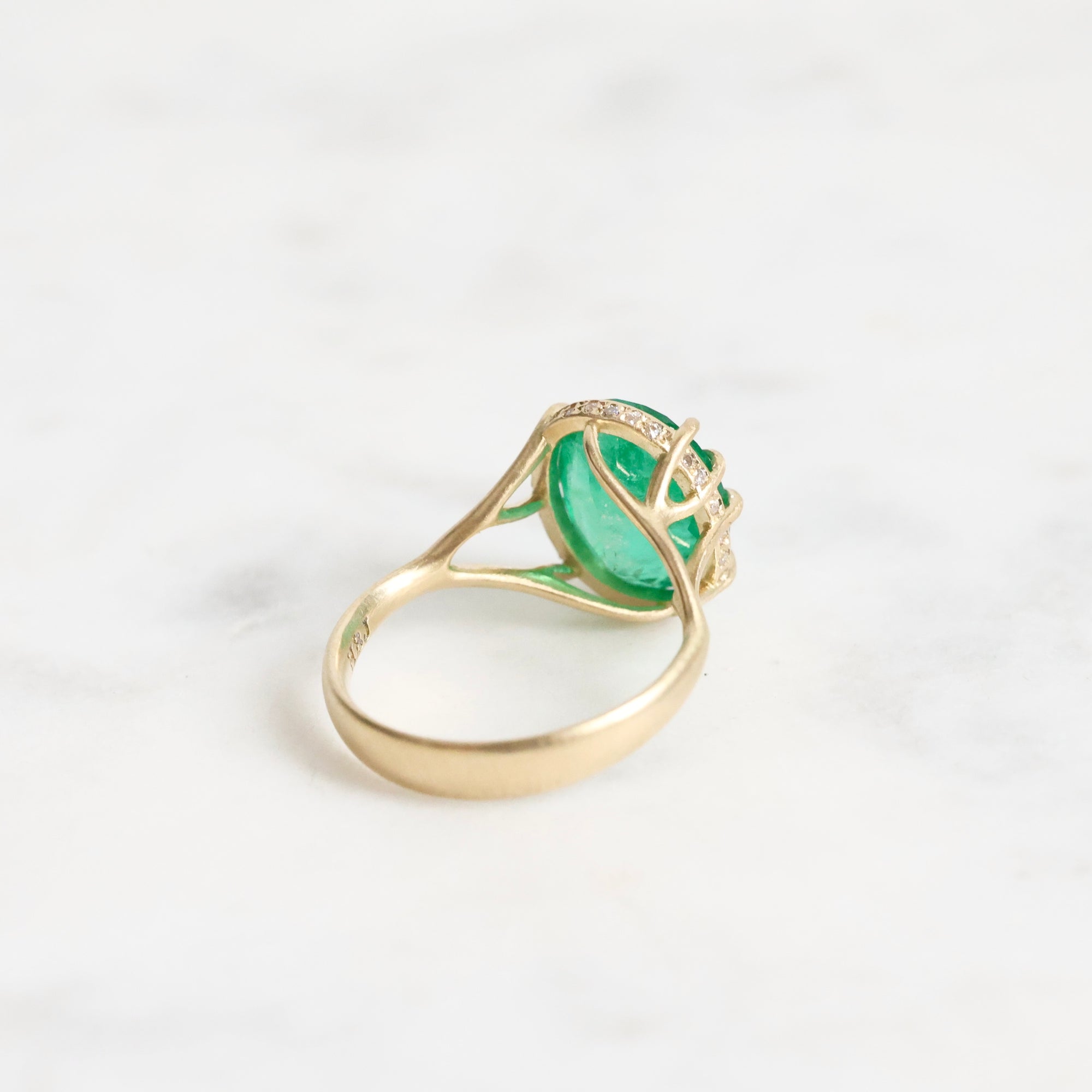 Large green gemstone ring with a diamond halo and branchy setting