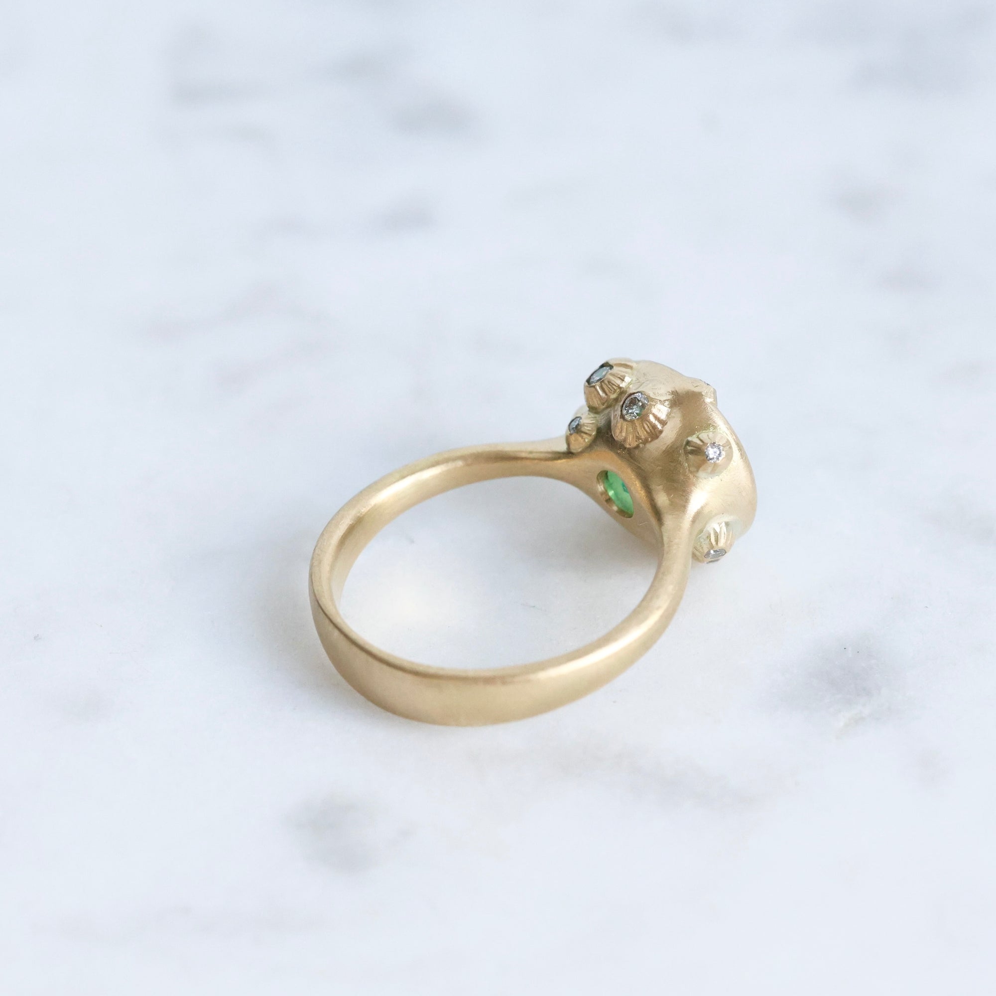 Large green gemstone ring surrounded by gold barnacles with diamonds 