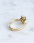 Large green gemstone ring surrounded by gold barnacles with diamonds 