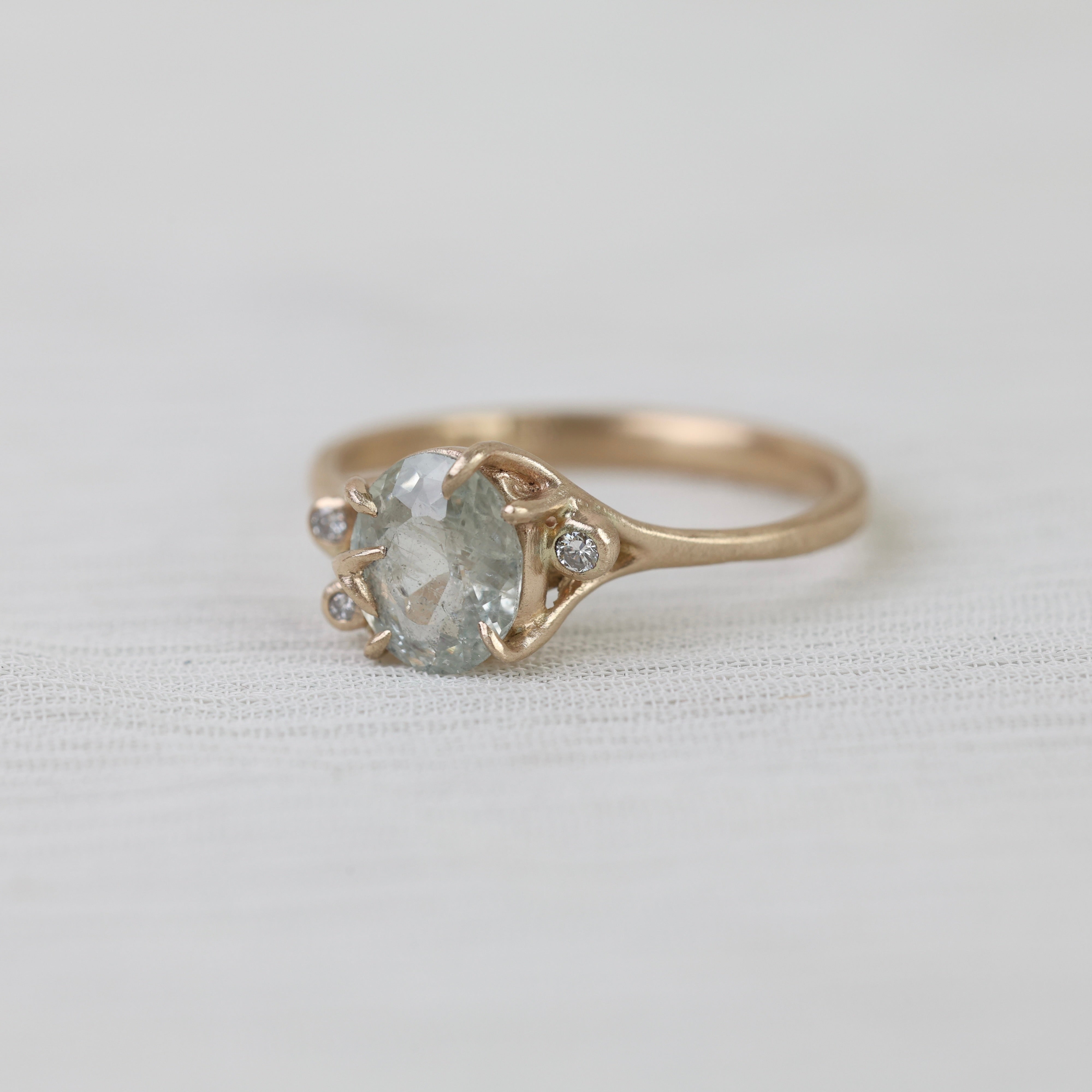 Gold ring with a large central gemstone and smaller stones on a light background
