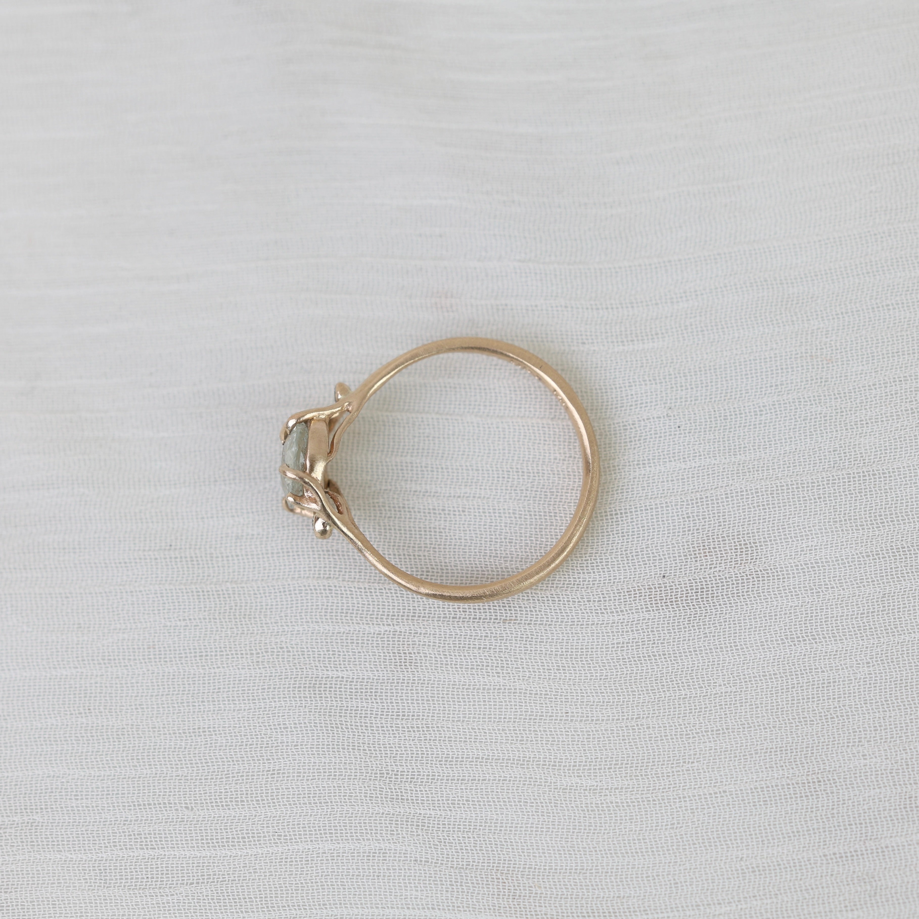 Gold ring with a gemstone on a light gray fabric background