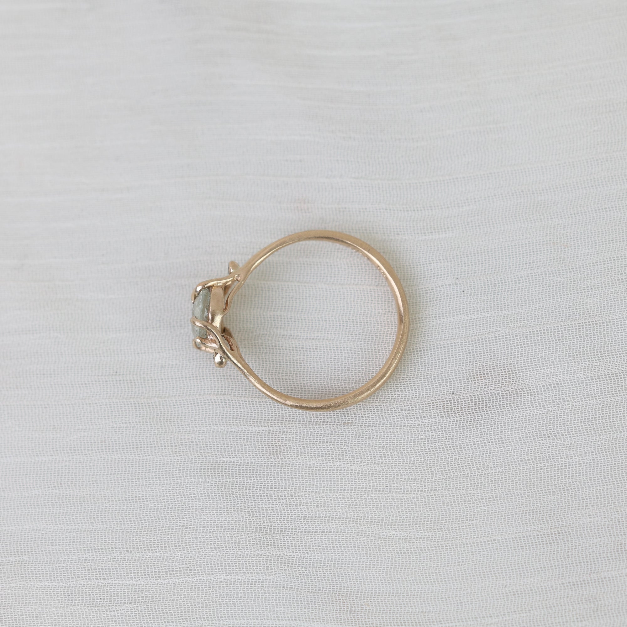Gold ring with a gemstone on a light gray fabric background