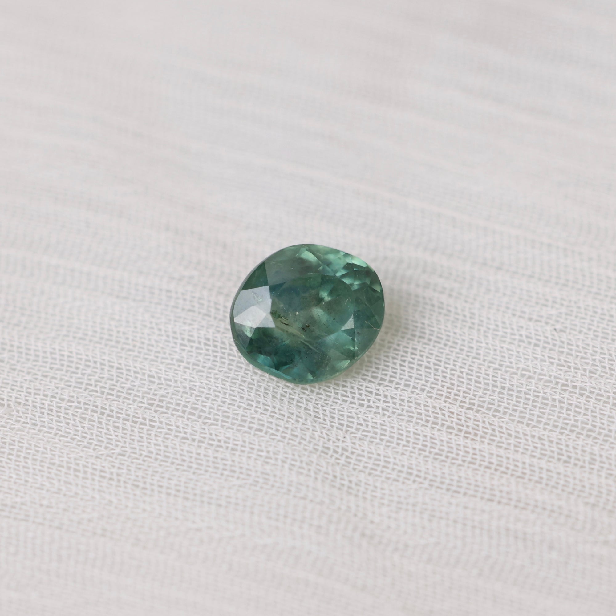 Green gemstone on a white fabric background