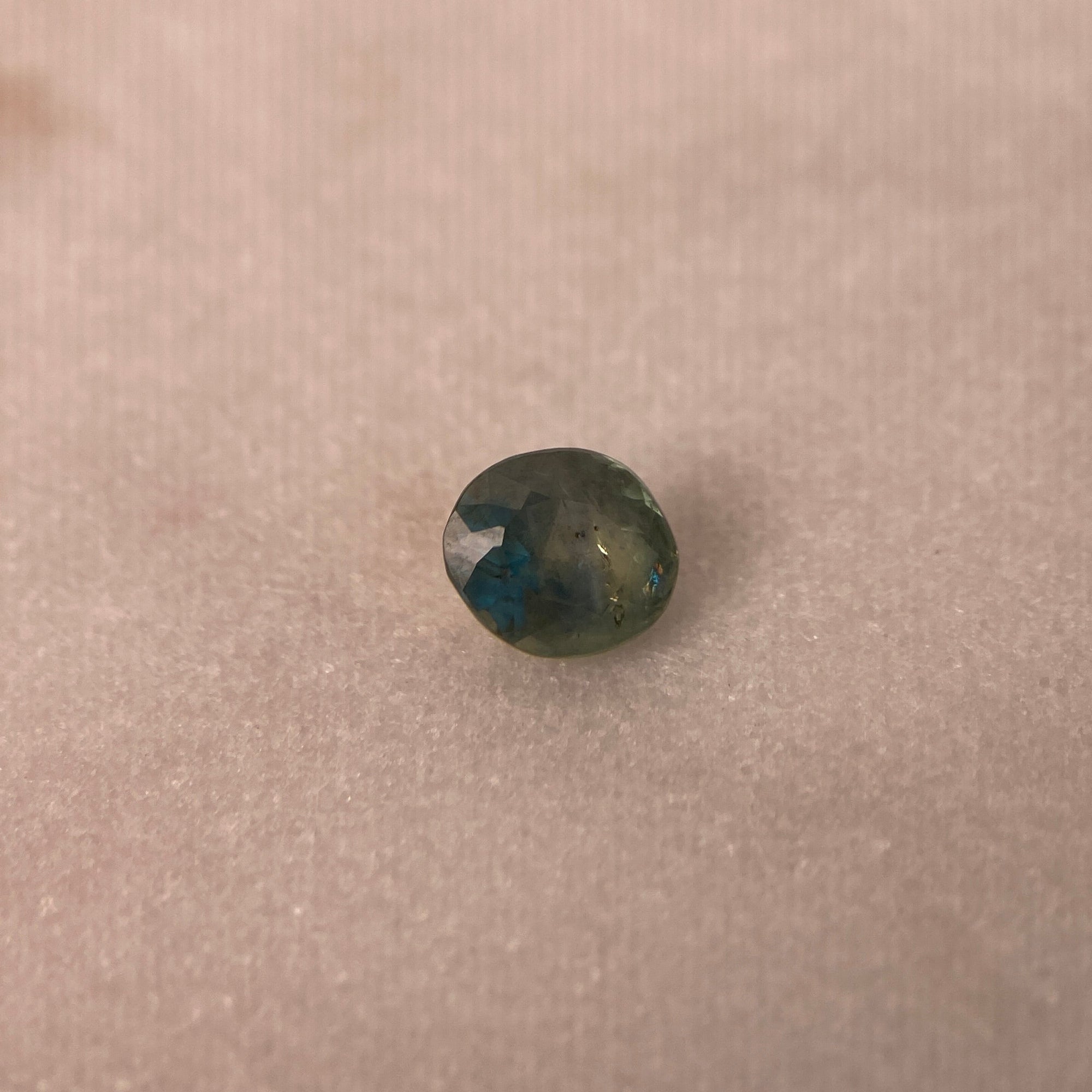 Greenish-blue gemstone on a beige background