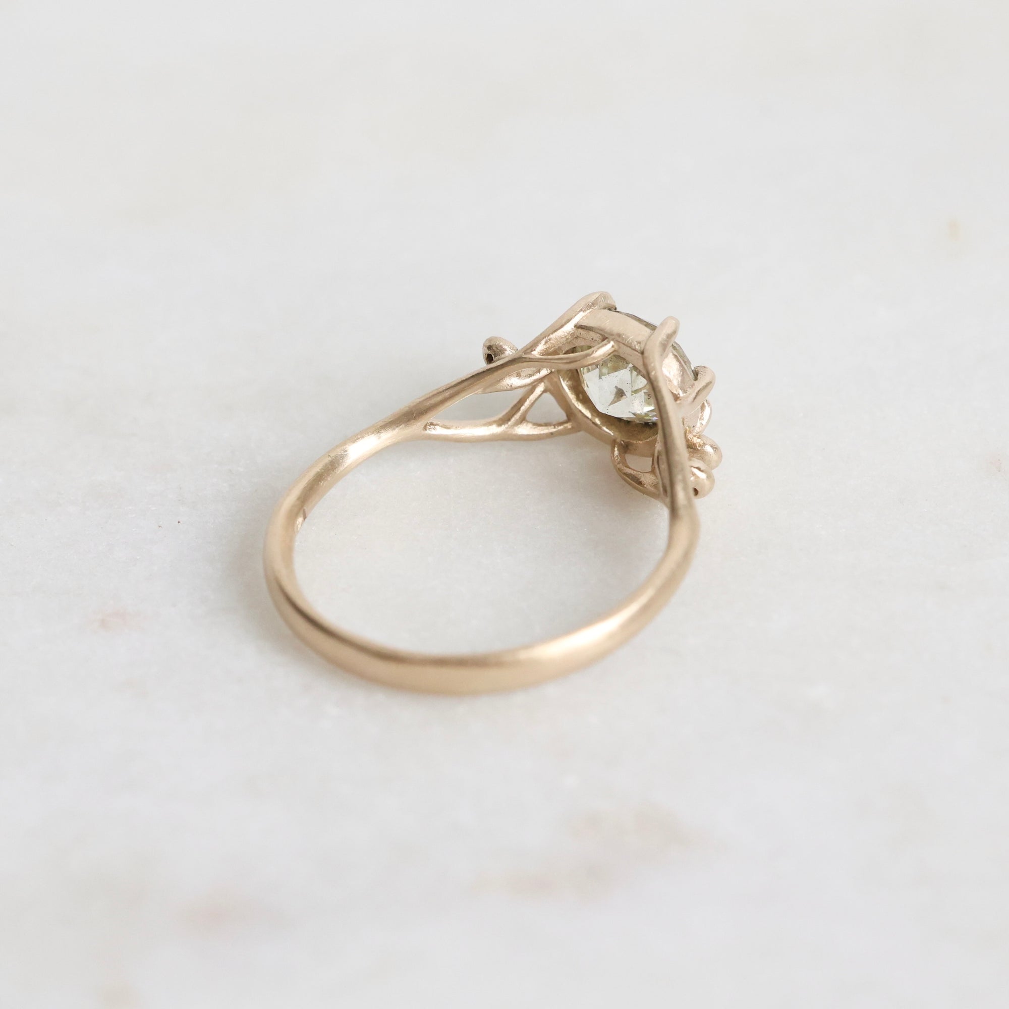 Gold ring with a diamond on a light gray background