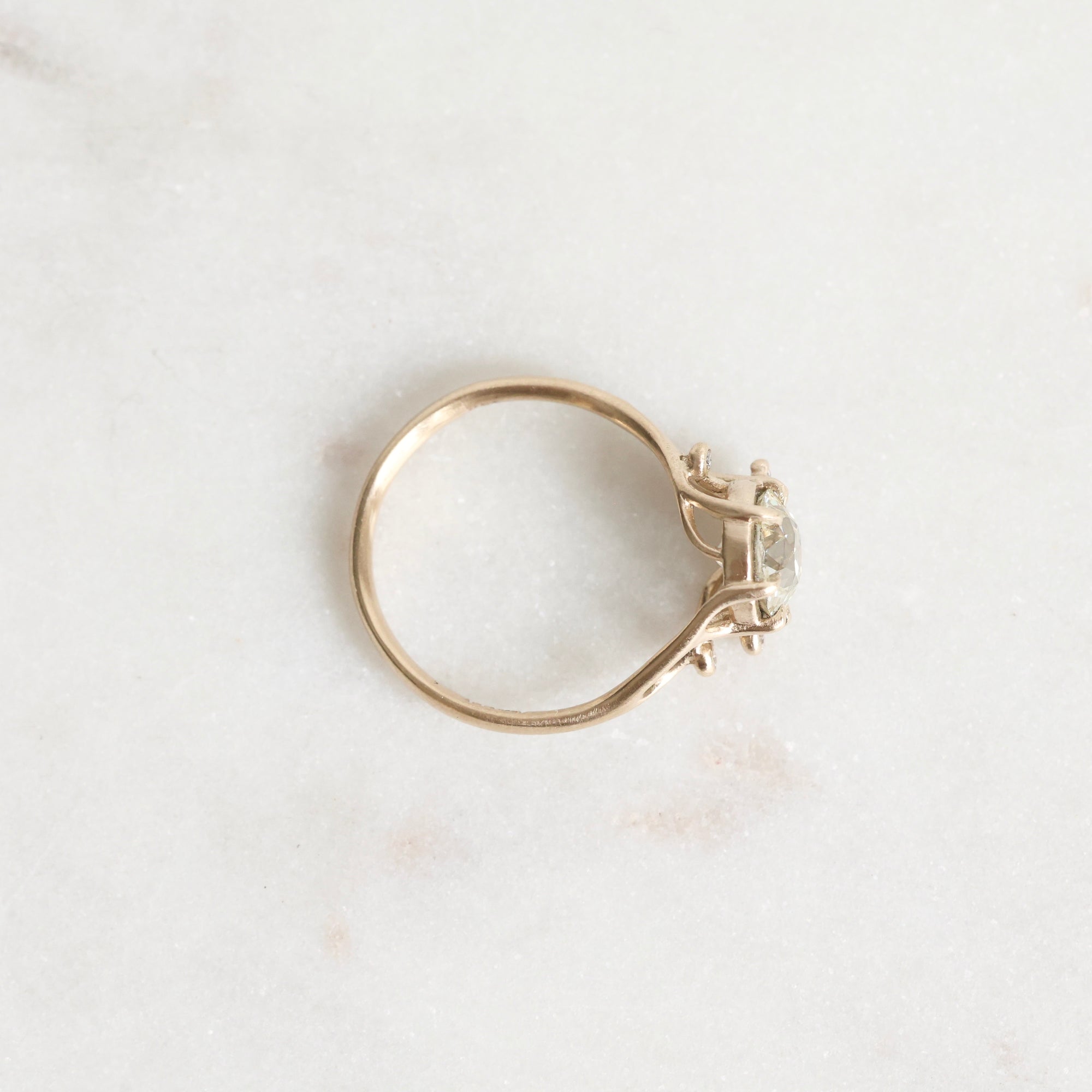 Gold ring with a diamond on a light marble background