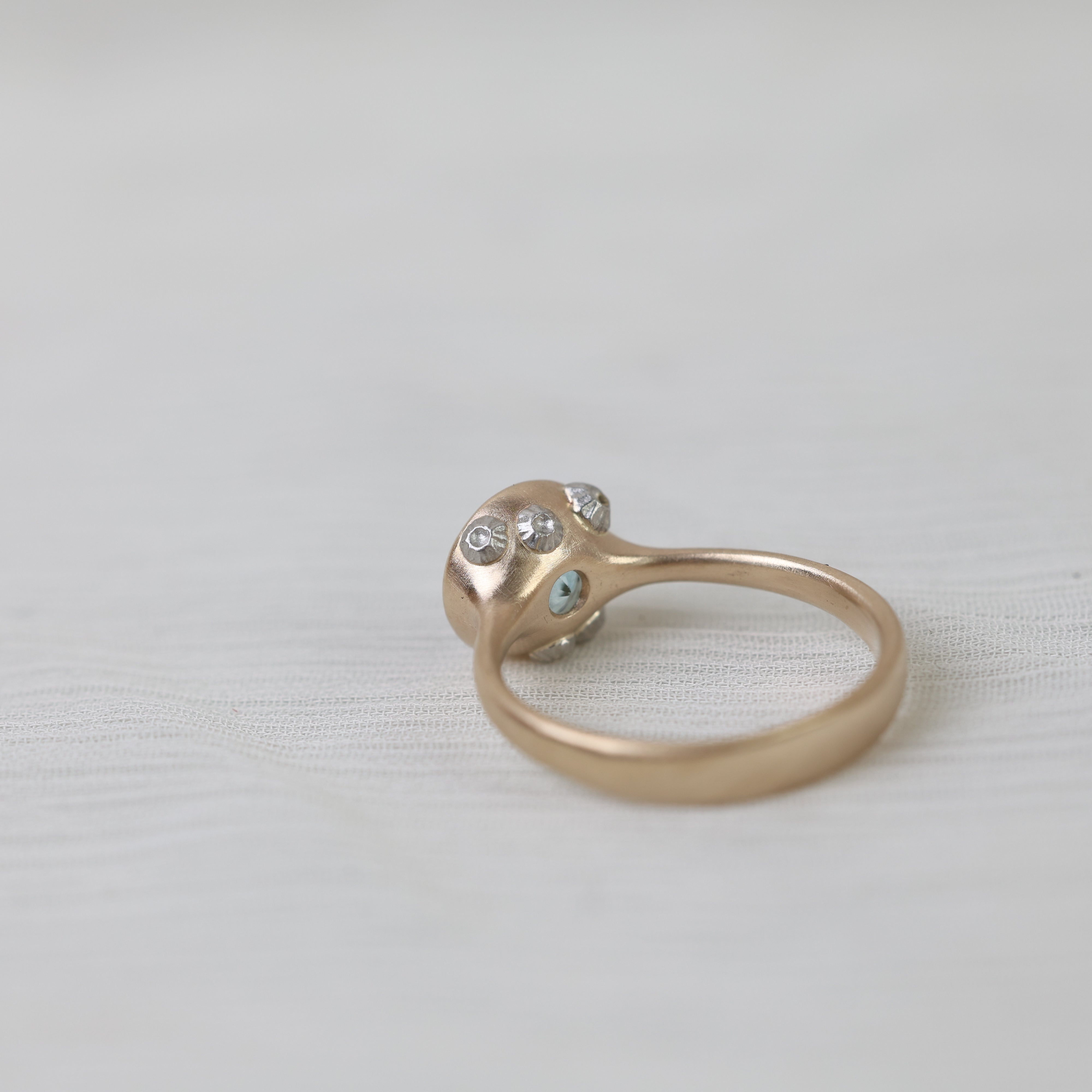 Gold ring with embedded barnacles on a light fabric background