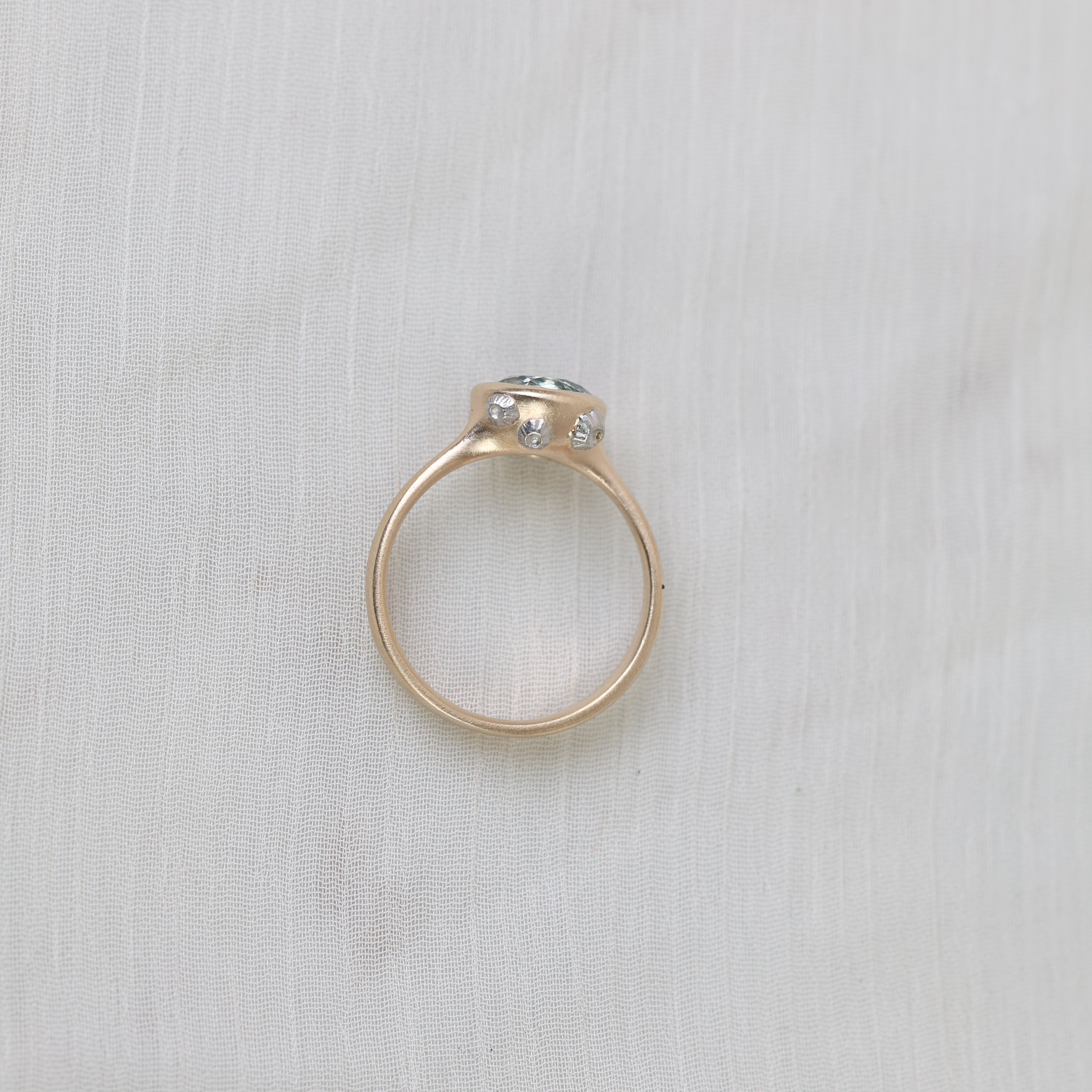 Gold ring with a gemstone on a light gray fabric background