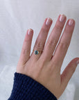 Hand wearing a gold ring with a blue gemstone on a white background